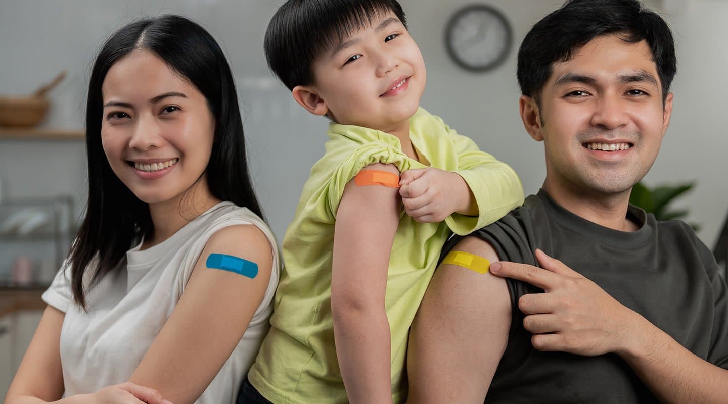 Mom, dad, and child post with their band aids after getting flu shots in the arms