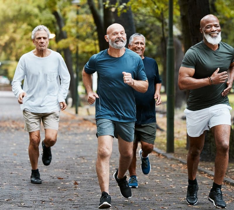 A group of four men job outside together