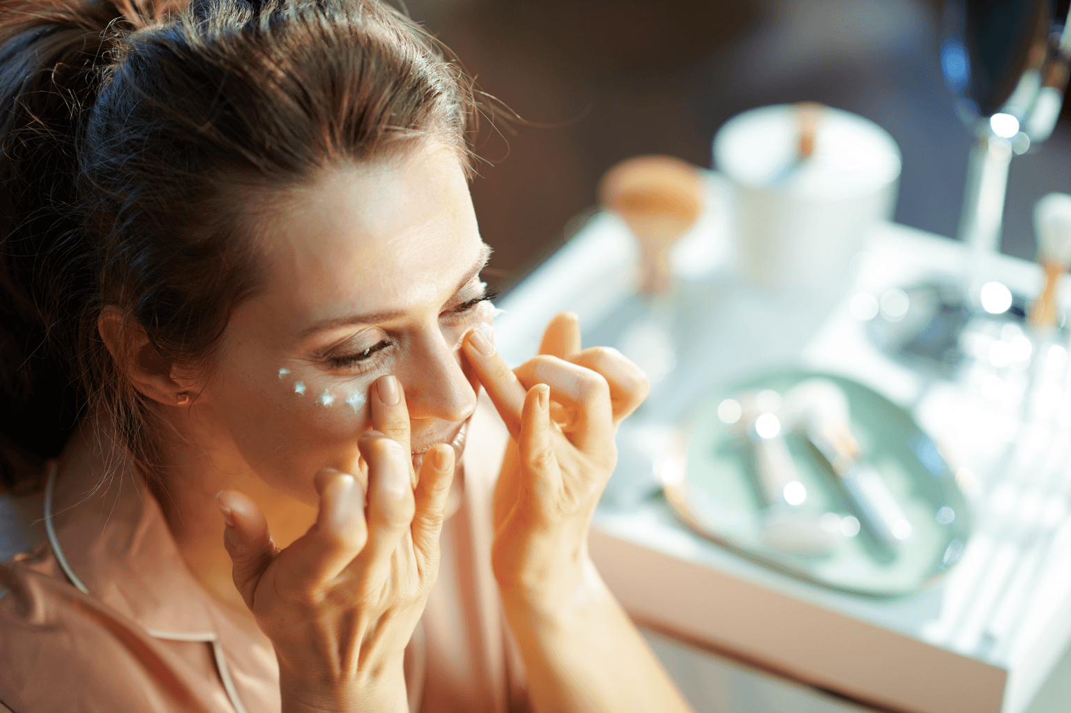woman applying eye cream in bathroom