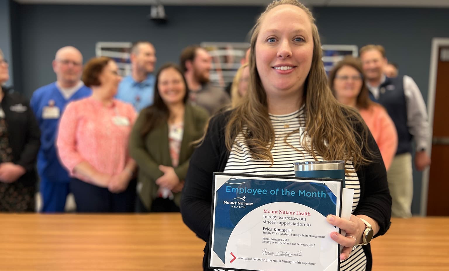 Erica Kimmerle poses with her employee of the month certificate in front of her coworkers