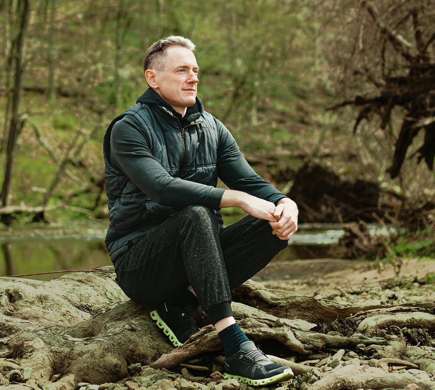 man sits on a log while out on a hike in the forest