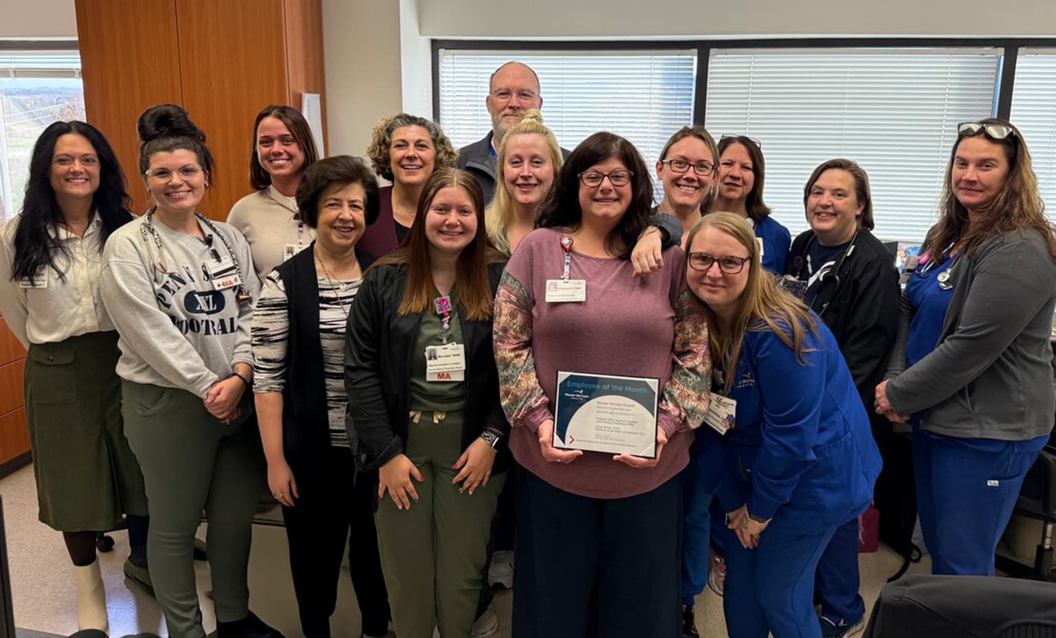 A group of colleagues surround Stephanie Miller to celebrate her being employee of the month