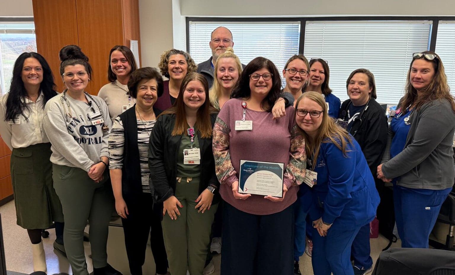 A group of colleagues surround Stephanie Miller to celebrate her being employee of the month