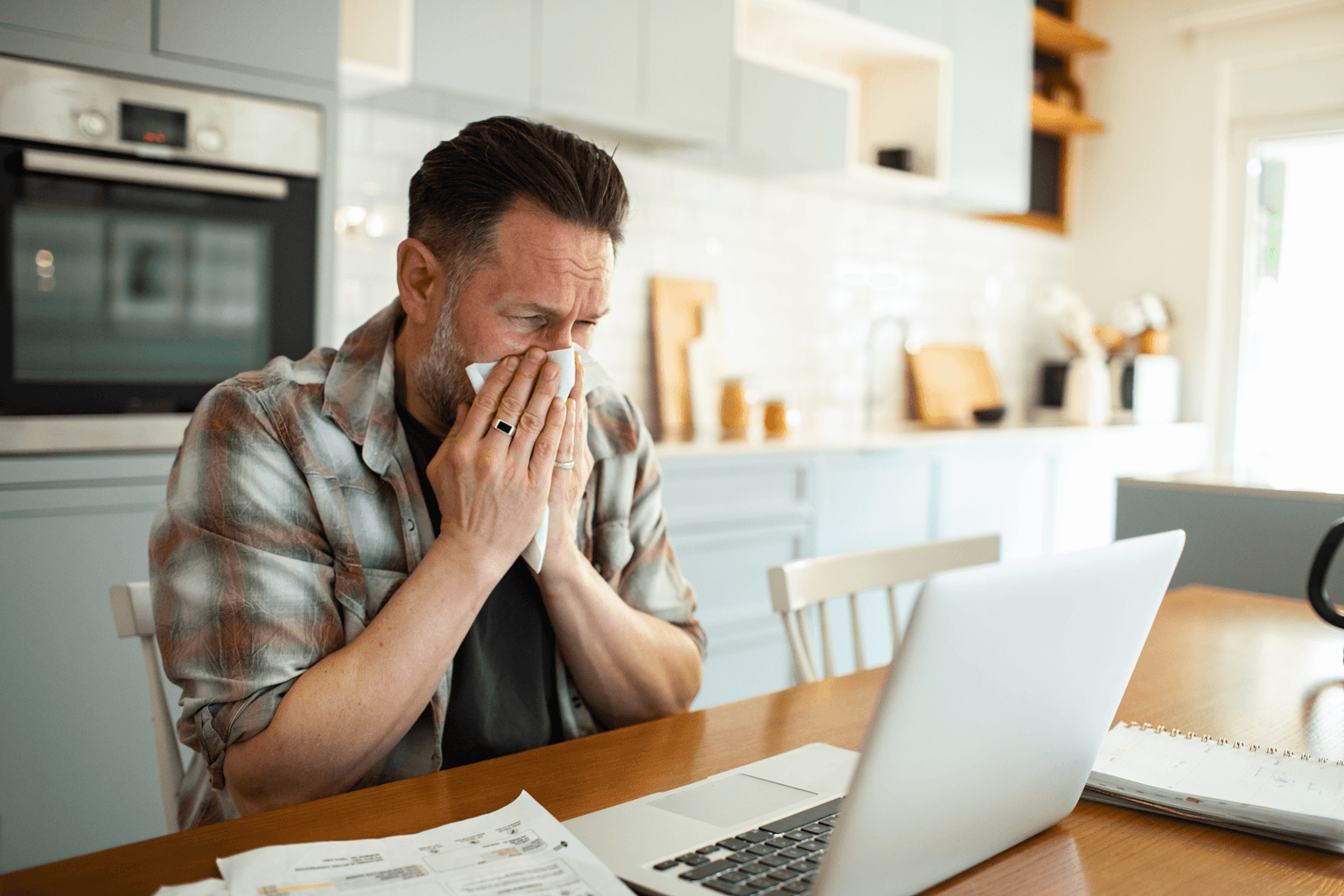 Man working from home on laptop with allergies