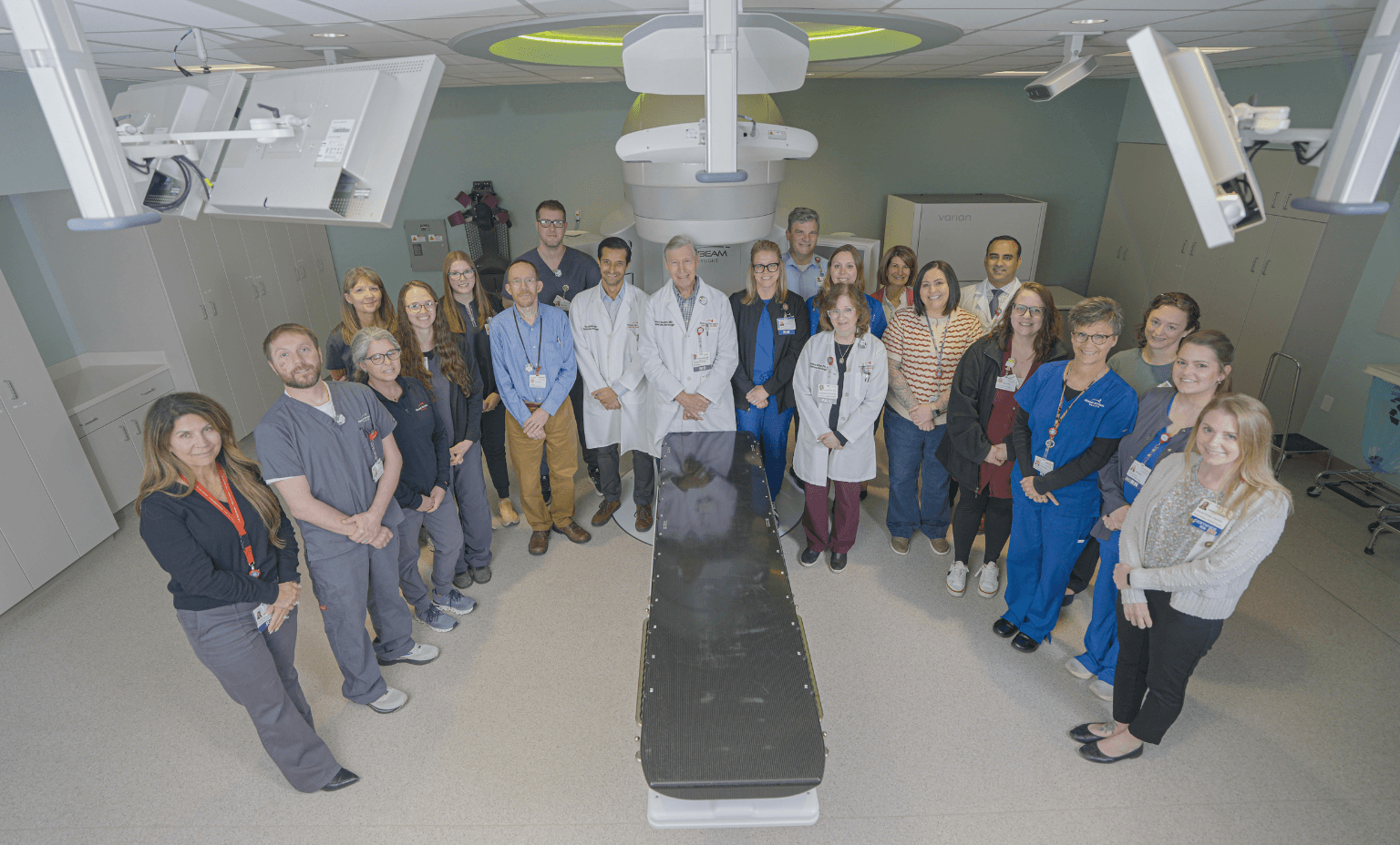cancer care team stands in front of TrueBeam linear accelerator